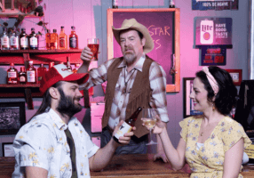 Three people toast drinks in a small-town bar, with liquor bottles and neon signs in the background.